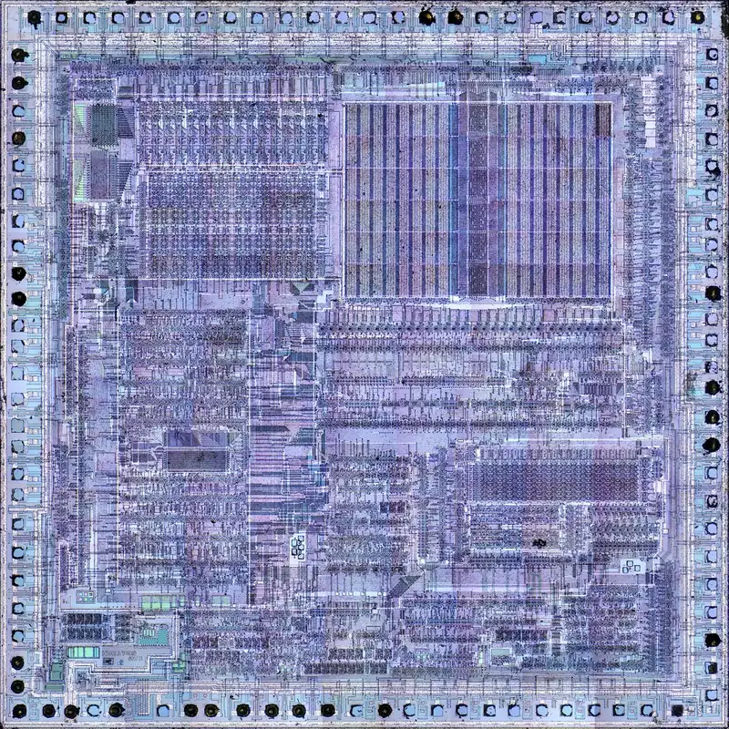 一颗微处理器的芯片表面（Hitachi HD61700，曾用在 Casio PB-1000 计算器里）。机器码再往下一层，就是这些刻在硅上的电路。